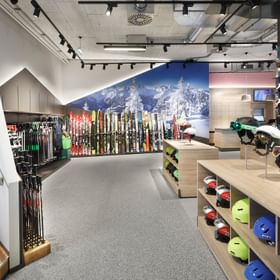 Skihelmets and skisticks in the front, colourful skiwall behind <br/>
