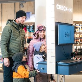 A family at the Bründl Sports ski rental check-in terminal 