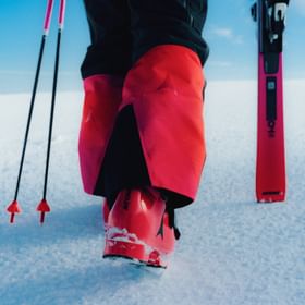 Skier wearing red Atomic Redster ski boots and pants on a snowy slope.