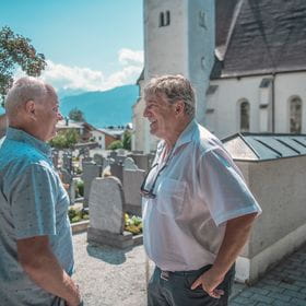 Manfred and Friedl standing at the graveyard and talking about their memories about Hans Bründl