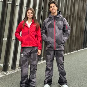 Zwei Team-Austria-Mitglieder tragen die offizielle AlphaTauri Olympia-Bekleidung 2026 mit dem österreichischen Wappen und Olympia-Ringen.