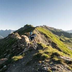 ein Mountainbiker fährt über ein Grat in den Bergen