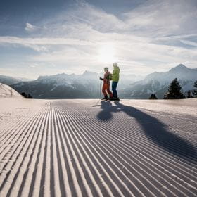 zwei Skifahrer stehen auf einer frisch präparierten Piste