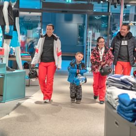 Eine Familie in Ski Bekleidung betritt ein Sportgeschäft 