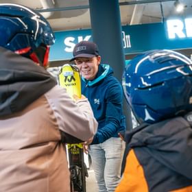 Two children pick up their rental skis in the Bründl Sports Shop 