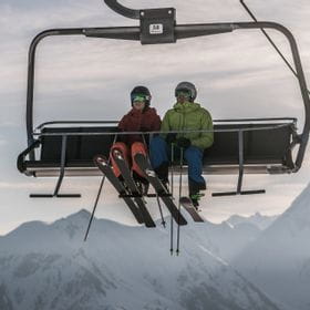 zwei Skifahrer sitzen in einem Sessellift