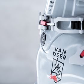 Das Bild zeigt eine Nahaufnahme des grauen Skischuhs von VAN DEER - Red Bull Sports. Deutlich erkennbar sind das markante Logo mit dem Hirsch sowie hochwertige Details wie die rote Metallschnalle und der Schriftzug "PRO 130 LV".