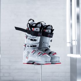 Auf dem Bild sind hochwertige Skischuhe der Marke Van Deer - Red Bull Sports zu sehen. Die Skischuhe haben ein modernes Design mit einer Kombination aus Weiß, Schwarz und roten Akzenten und stehen auf einem minimalistischen Display.