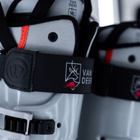 Auf dem Bild ist die obere Partie des grauen Skischuhs von VAN DEER - Red Bull Sports zu sehen. Besonders auffällig ist das elastische Band mit dem markanten Logo, das für einen festen Halt sorgt und gleichzeitig das moderne Design unterstreicht.