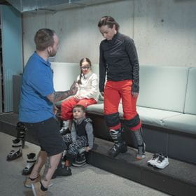 a woman tries a skiing shoe, while a employee gives her advice