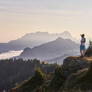 ein Trailläufer blickt in die Ferne und genießt den Ausblick auf die Alpen