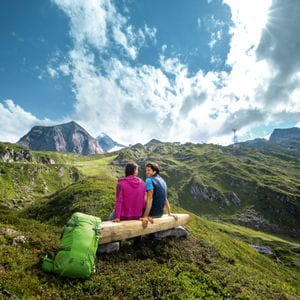 zwei Wanderer sitzen auf einer Bank in der Berglandschaft