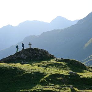 three hikers are climing a hill in a mountain landscape