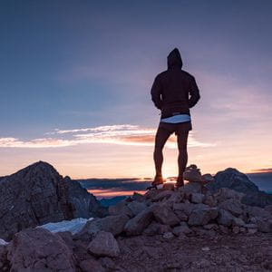 ein Läufer betrachtet den Sonnenuntergang in den Bergen