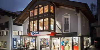 Beleuchtetes Schaufenster des Bründl Sports Saalbach Zentrum Shops - Abendaufnahme <br/>