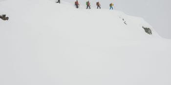 Eine Gruppe von Menschen besteigen den Berg im Winter um an einem Lawinenkurs teilzunehmen.
