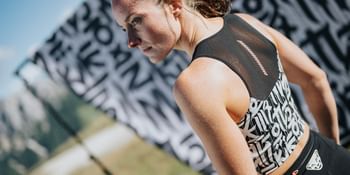 Dynafit female trail runner wearing lightweight performance apparel during alpine trail run.