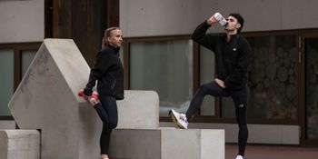 A young couple takes a brief break to drink water after jogging