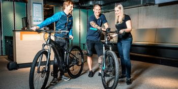 A couple is renting bicycles which are handed over to them by an assistant