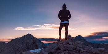 ein Läufer betrachtet den Sonnenuntergang in den Bergen