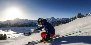 ein Skifahrer auf der Piste mit starker Schräglage