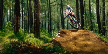 Downhiller jumps over a tramp in the forest