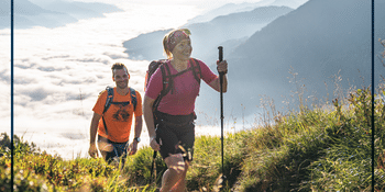 BRÜNDL +CARD Key Visual - Ein glückliches Paar genießt eine sommerliche Wanderung in den Bergen.
