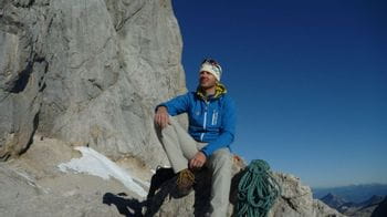 Ortovox Mountain Guide Wolfgang Rohrmoser sitting on a rock in the mountains