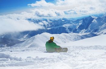 Snowboarder bei Pause sitzend auf Schnee