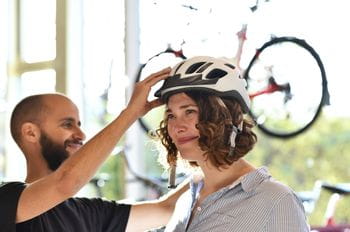 a woman is fitting on a bycicle helmet