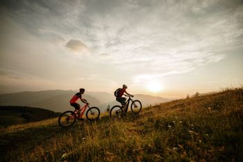 Bikers driving uphill during a sunset