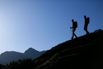zwei Wanderer steigen einen Hang hinab in Schladming