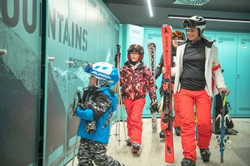 Eine Familie geht nach einem Skitag ins Bründl Sports Skidepot und lagert dort ihre Ski und Skischuhe ein 