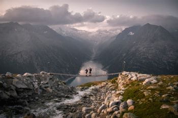 two hikers on a suspension bridge in the mountains