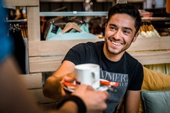 Happy man who is served a coffee at Bründl Sports