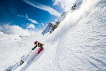 A woman is skiing through powder next to the slopes