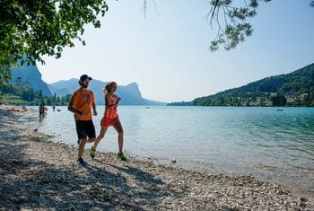 ein Mann und eine Frau laufen entlang eines Seeufers