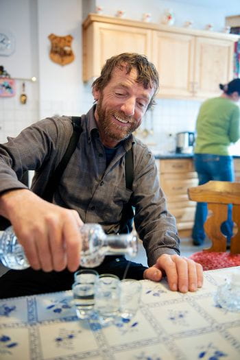 A laughing man handing out homemade schnapps