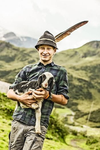 Ein junger Mann mit einem Schaf im Arm.