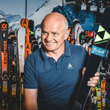 Manfred Rogetzer, Leiter Bründl Sports Racing Service, mit Fischer Ski vor einer Skiwand