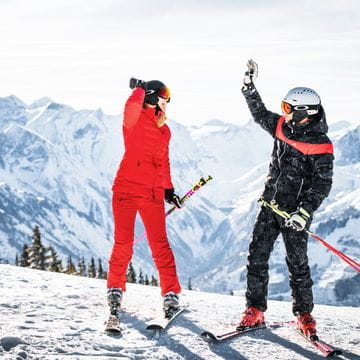 Skifahrer auf der Schmittenhöhe die sich einklatschen mit dem Kitzsteinhorn im Hintergrund