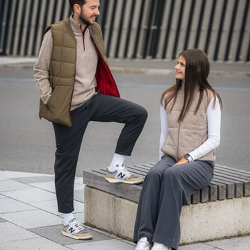 Zwei Personen spazieren durch die Stadt in nachhaltiger Ecoalf Mode – gesteppte Westen in Beige und Khaki, kombiniert mit modernem urbanem Stil.