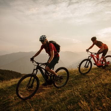Radfahrer fahren den Berg runter bei einem Sonnenuntergang