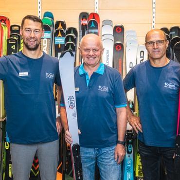 Brian Dettenbeck, Manfred Rogetzer und Hans Hofer vor einer Skiwand.