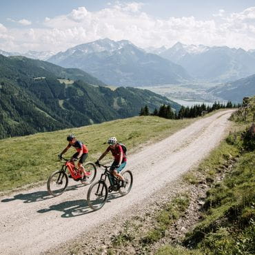 Zwei Radfahrer fahren den Berg auf einer Schotterstraße hoch.