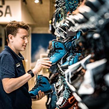 ein Lehrling ordnet Schuhe ins Regal ein