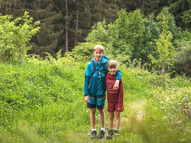 Two children standing in the forest