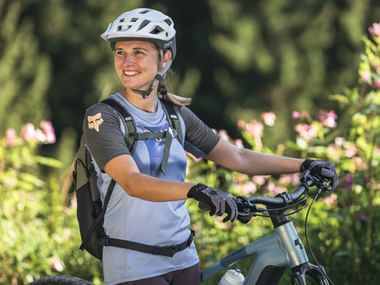 A young woman stands atop the mountain after a biking excursion