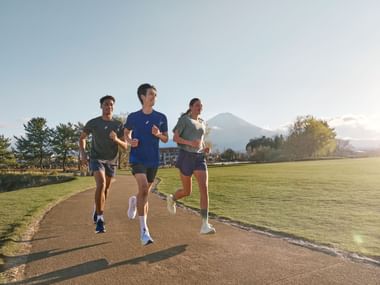 Three runners on a path in the sunshine, mountains in the background