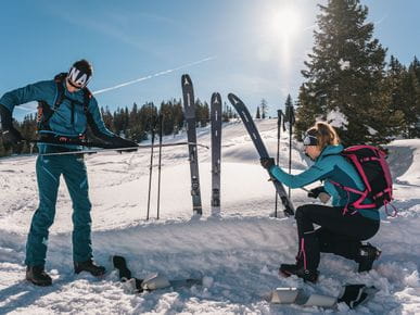 Zwei Personen bereiten sich auf ihre Skitour vor.